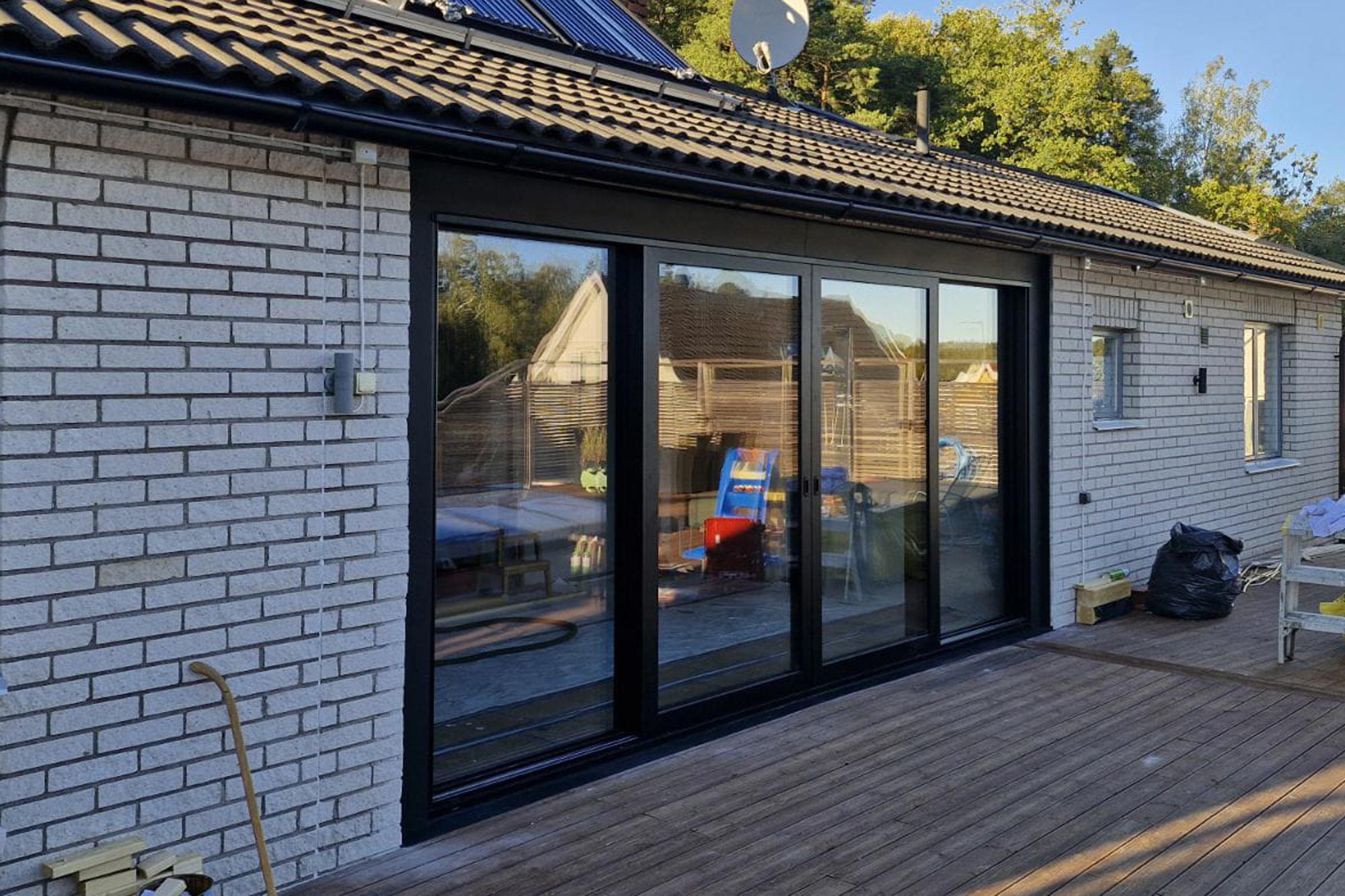 Tegelhus med nybyggda, stora skjutdörrar i glas till altanen