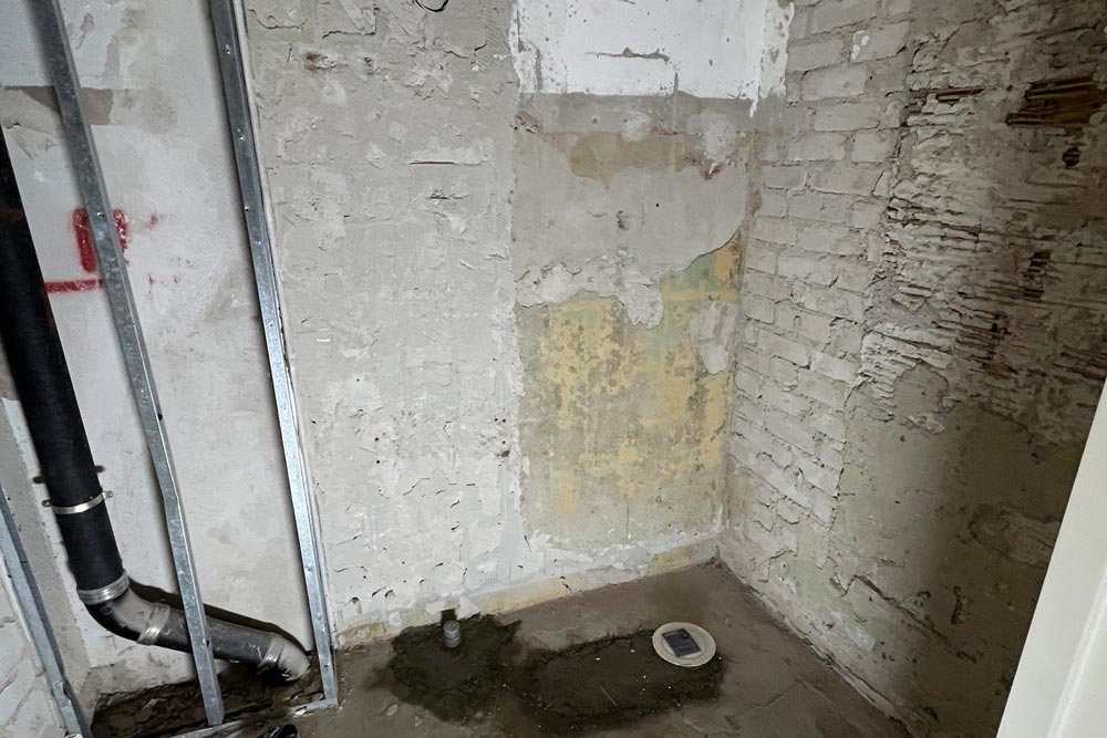 Badrum innan renovering, med bara väggar och golv i betong